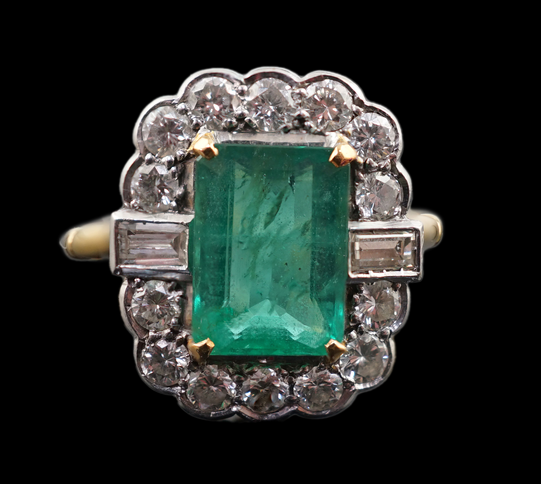 An Art Deco style yellow metal, emerald and diamond set oval cluster ring